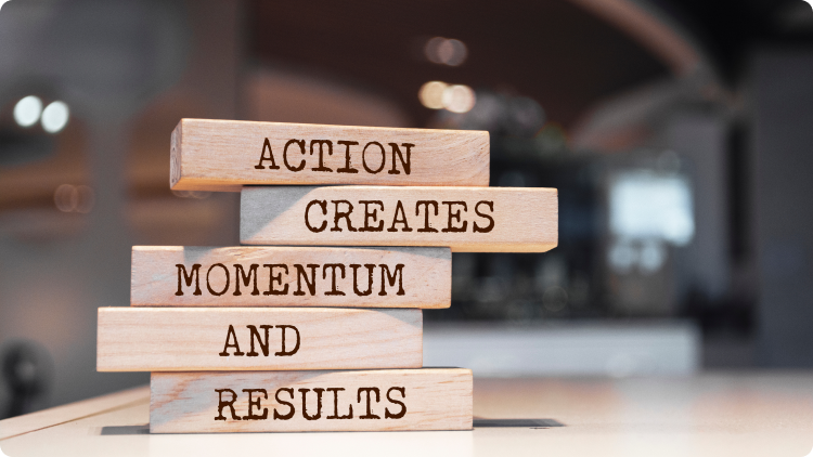 In the foreground, wooden bricks are arranged, creating a blurred effect against the background. The text on the bricks reads: "Action creates momentum and results."