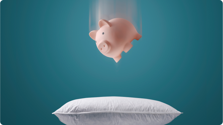 salvadanaio che cade sopra un morbido cuscino, che simboleggia il risparmio e la sicurezza finanziaria