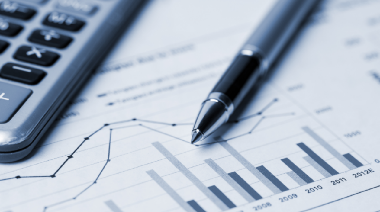 Un stylo et une calculatrice sur la carte de papier avec des graphiques et des chiffres.