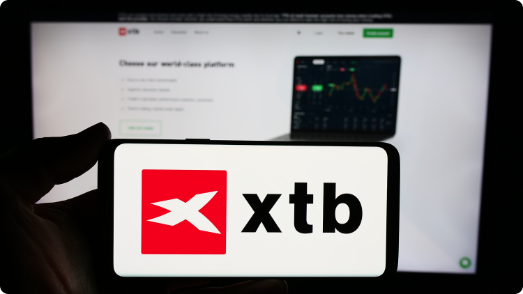 logo xtb na mobile av pozadÃ­ na notebooku vzdelÃ¡vacia platforma xtb