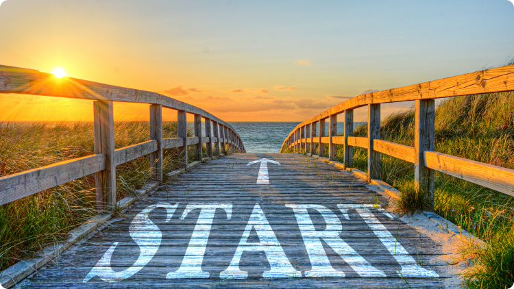A seaside sunset with a wooden side walk with a white arrow and a word âstartâ on it