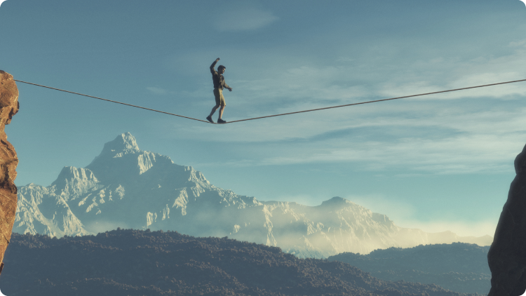Homem jovem a caminhar em equilÃ­brio, entre as montanhas, com o cÃ©u azul em fundo.