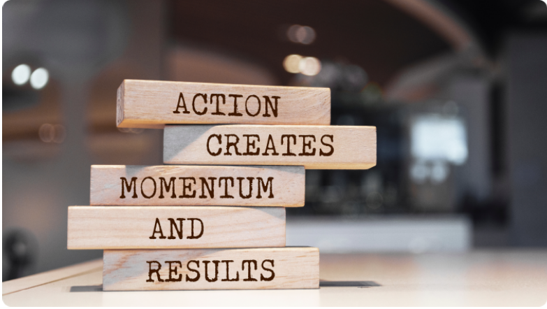 Un arriÃ¨re-plan flou avec des briques placÃ©es Ã  l'avant. Les briques sont en bois et portent le texte Â« l'action crÃ©e l'Ã©lan et les rÃ©sultats Â».