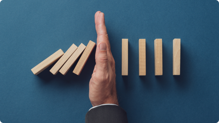 Una mano che cerca di fermare un domino che cade  