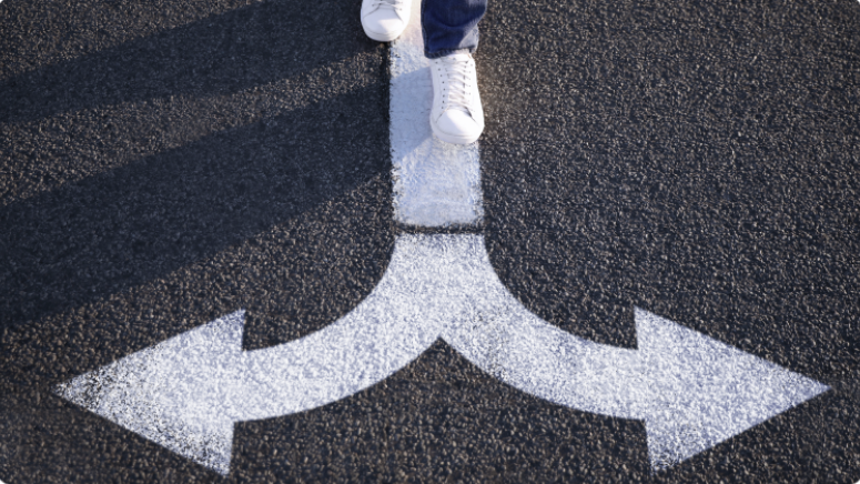 Personne debout sur une route avec une flÃ¨che blanche pointant vers la gauche et la droite, symbolisant la prise de dÃ©cision