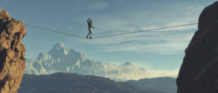 Jeune homme marchant en Ã©quilibre, entre les montagnes, avec le ciel bleu en arriÃ¨re-plan.