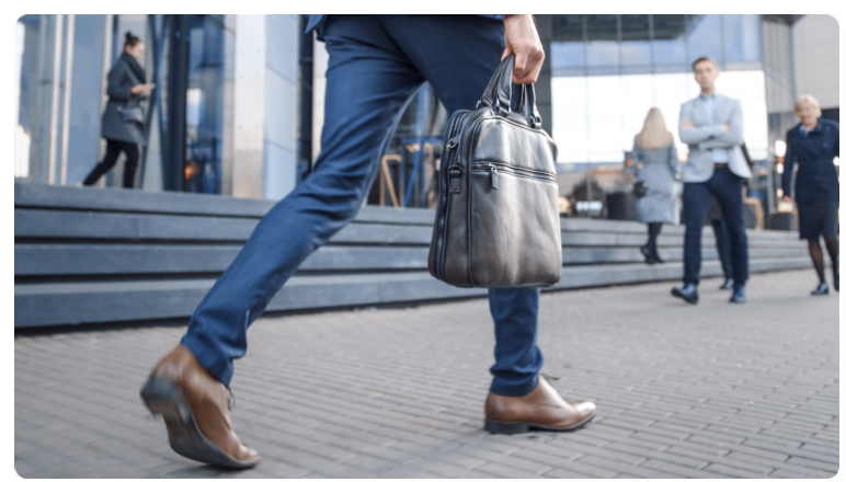 Un homme d'affaires en costume-cravate qui marche d'un pas assurÃ© dans une rue de la ville.