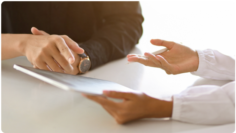 Deux personnes assises Ã  une table, regardant ensemble lâÃ©cran dâune tablette