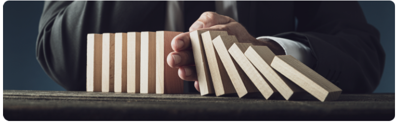 Un homme vÃªtu dâun costume saisit des blocs de bois comme des dominos, les empÃªchant de tomber plus bas, reprÃ©sentant ainsi professionnalisme et gestion des risques dans son travail.