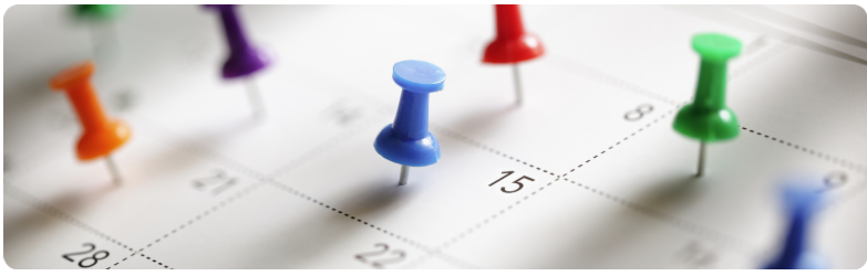 Un calendrier mural marquÃ© dâÃ©pingles colorÃ©es indiquant les dates et Ã©vÃ©nements importants tout au long du mois